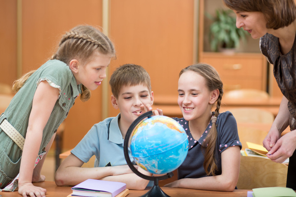 Dwie dziewczynki i chłopiec podczas lekcji geografii