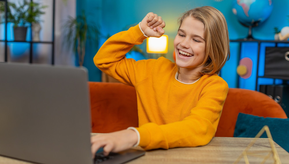 Uśmiechnięty nastolatek przy laptopie w domu